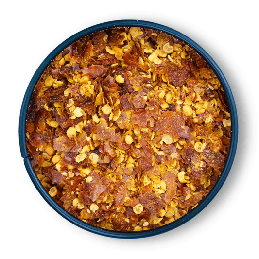 Pequin Chili gemahlen in rundem Behälter vor weißem Hintergrund.