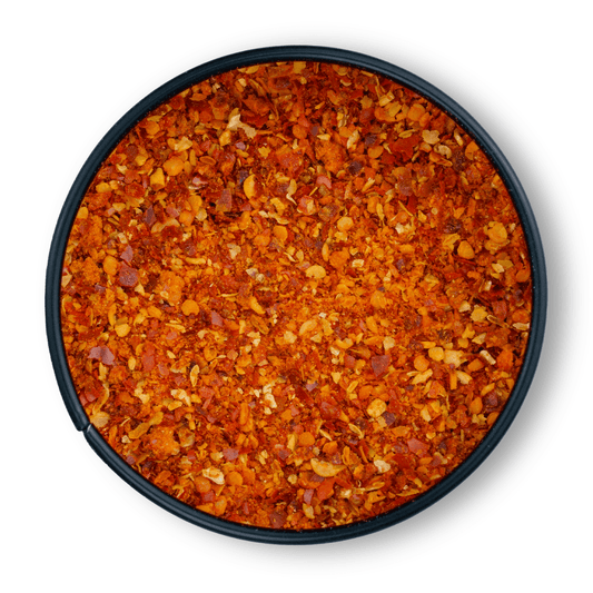 Runde schwarze Schale mit leuchtend orange-roten Bio Piment dEspecial Chiliflocken von oben.