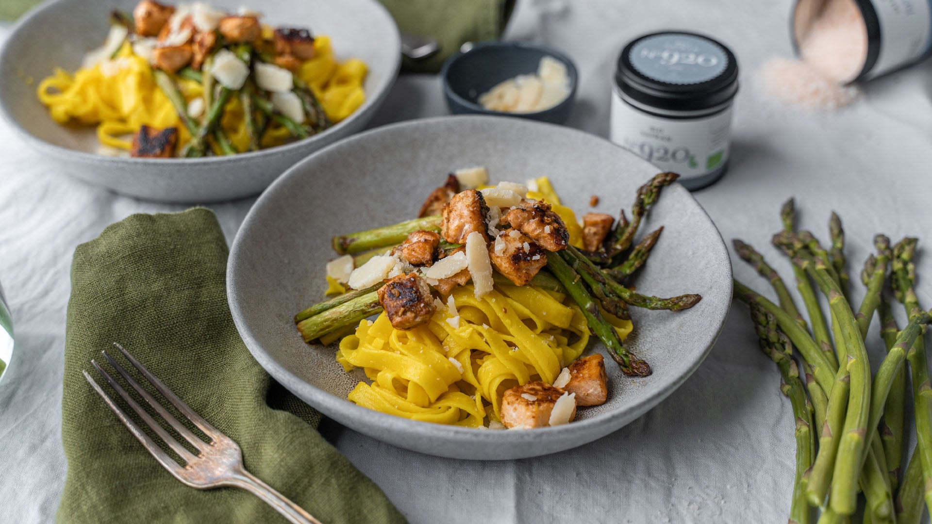 Gelbe Nudeln mit Lachs, Spargel und Parmesankäse auf einem Teller.
