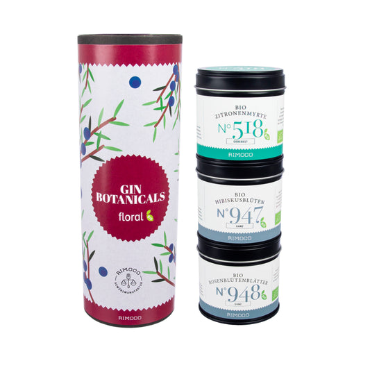 Drei gestapelte Dosen Bio-Tee 518, 947 und 948 in einer floralen Bio Gin Botanicals-Röhre.