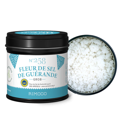Schwarze, zylindrische Dose mit grobem, weißem Fleur de Sel aus Guérande.