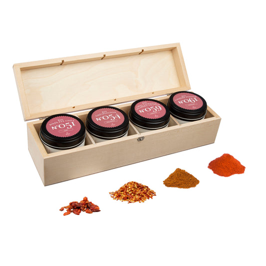 Chili Geschenkbox aus Holz mit vier Gewürzgläsern, darin Chiliflocken und weitere Gewürze sichtbar.