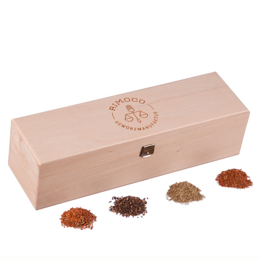 Grillgewürze Geschenkbox N°1 mit Verschluss, davor vier Haufen gemischter Gewürze.