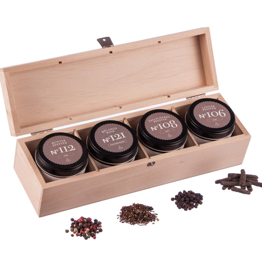 Holzbox mit vier beschrifteten Gewürzdosen, darunter eine Dose Mélange Noir.