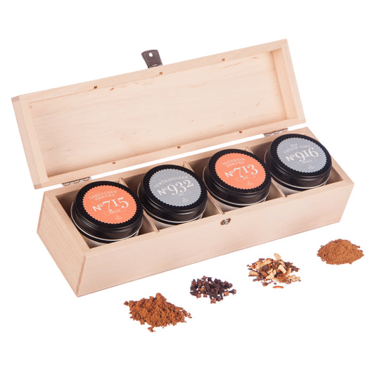 Holzbox mit vier Teedosen, Bio Ceylon Zimt, loser Tee und sichtbare Gewürze davor.