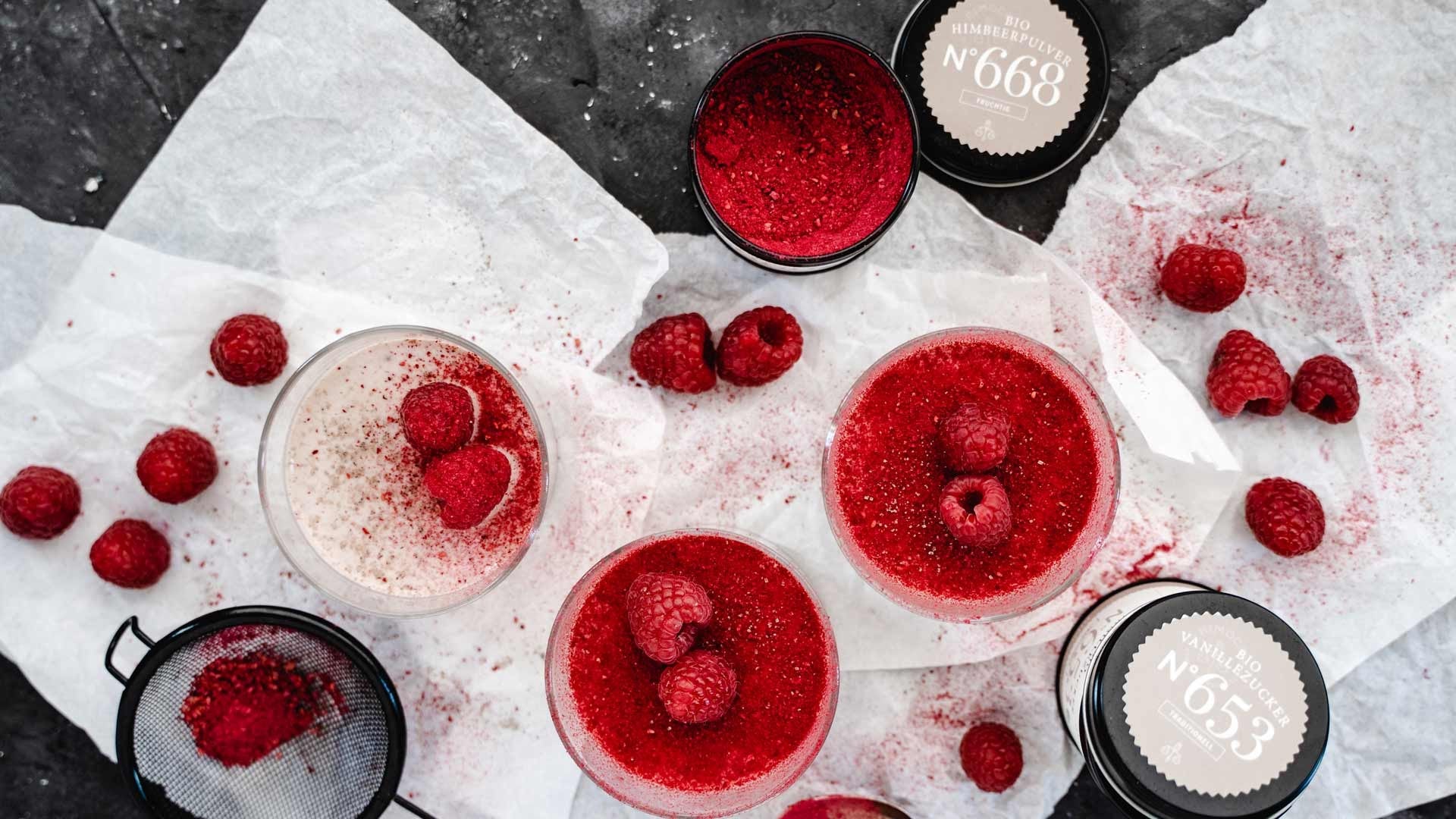 Himbeerdesserts mit frischen Himbeeren, Himbeerpulver und Dosen mit Vanillezucker.