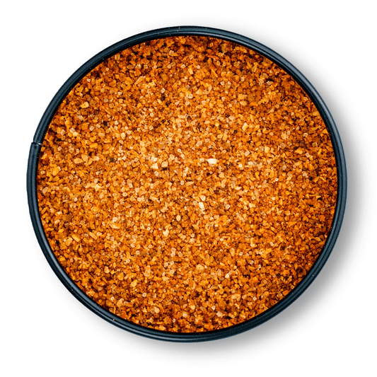 Rundes, schwarzes Gefäß mit grobem, orange-braunem Bio Magic Dust Rub von oben gesehen.