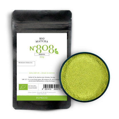 Schwarzer Beutel Bio Matcha Tee neben einer Schale mit grünem Matcha-Pulver.