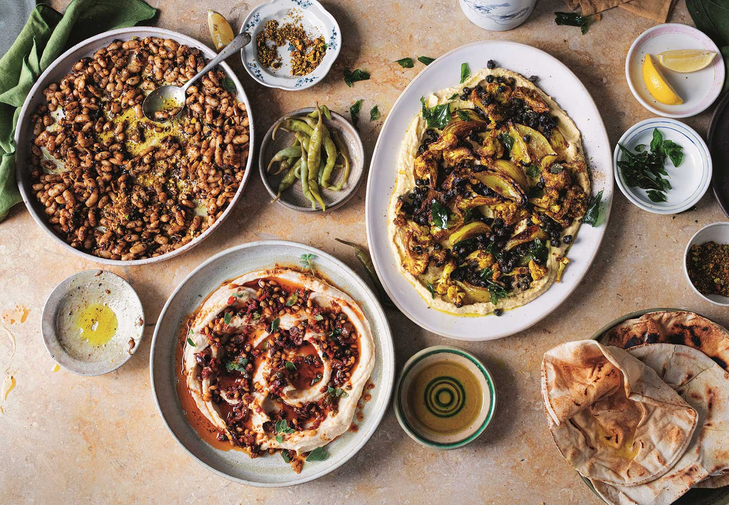 Schalen mit Hummus, Bohnen und Fladenbrot auf einem Tisch, inspiriert von „Ottolenghi Simple Too“.