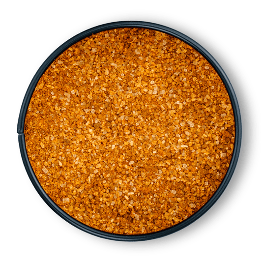 Runde schwarze Schale mit grobem orange-braunem Bio Pulled Pork Rub, von oben auf Weiß gesehen.