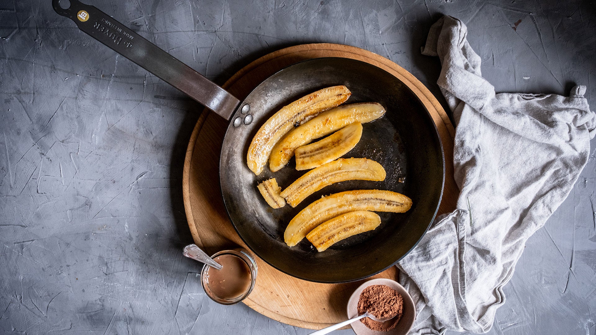 Gebratene Bananenscheiben mit Schokoladensoße und Kakaopulver bestreut.