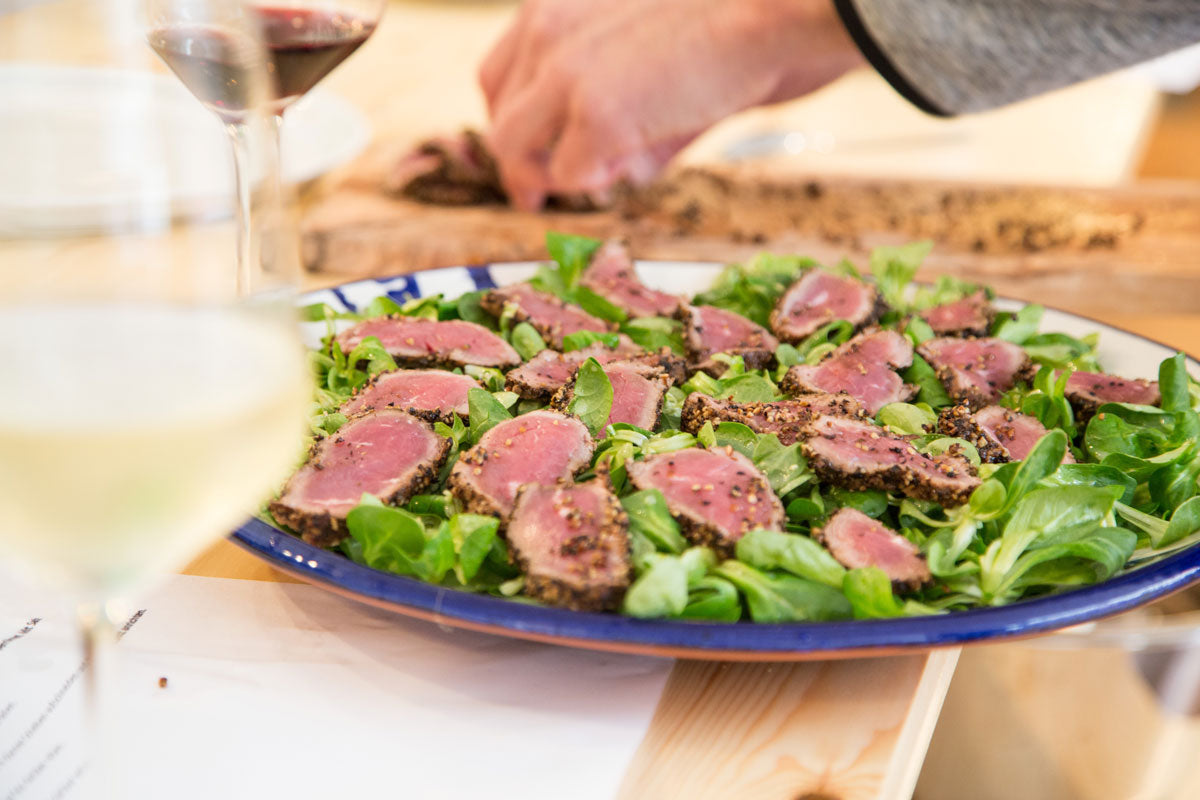 Gebratener Thunfisch auf Salat, eine Hand richtet an, Weingläser auf einem Gewürzseminar Italien.