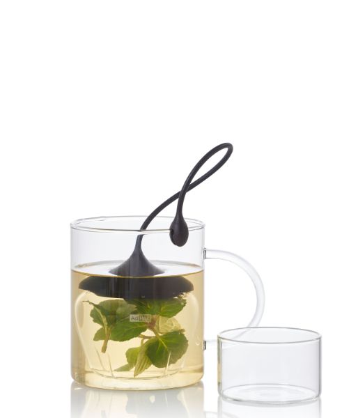Teefilter Fusion von AdHoc in einem Glas mit Tee und Kräutern, daneben ein transparenter Deckel.