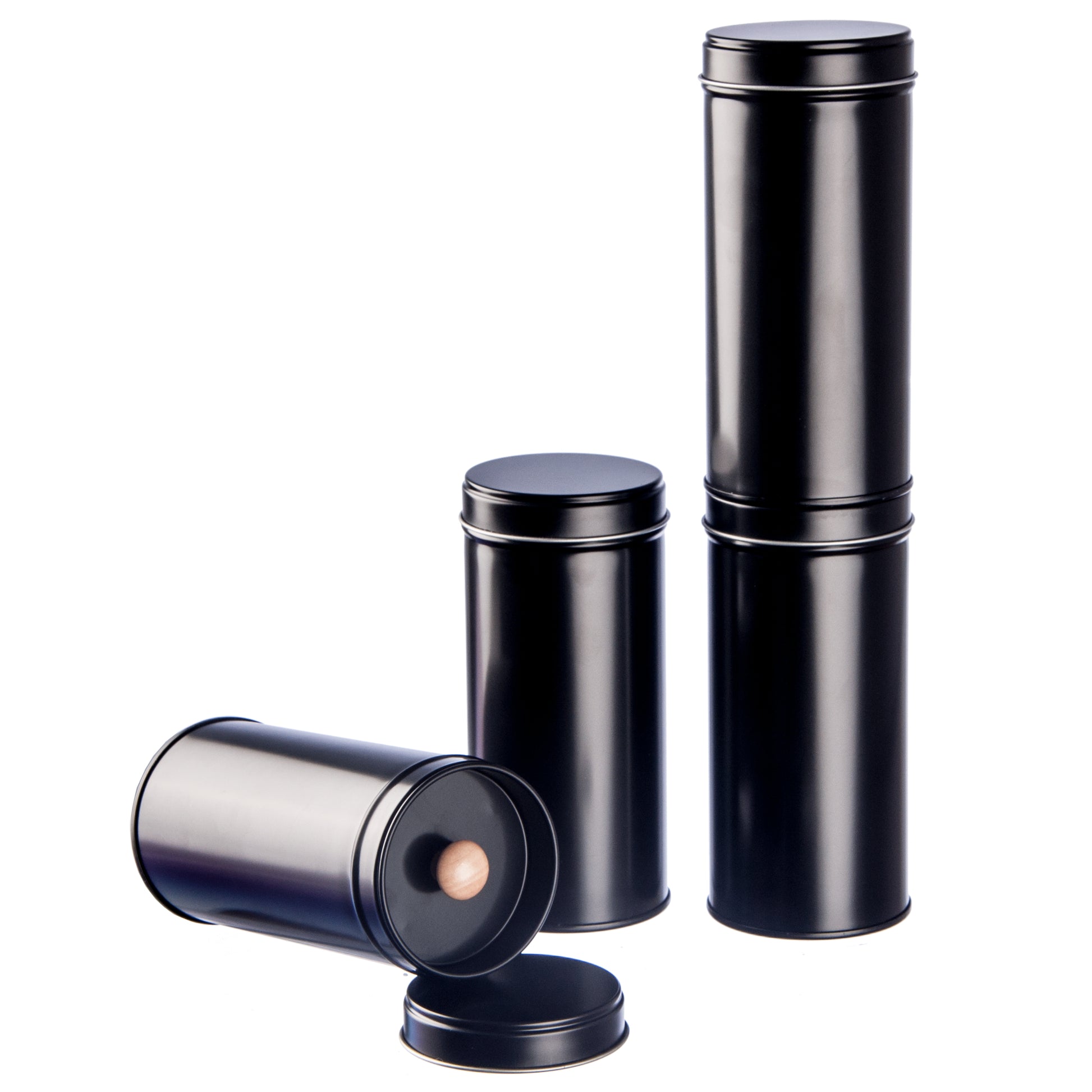 6 schwarze Teedosen mit Aromadeckel und 6 Etiketten, nebeneinander stehend.