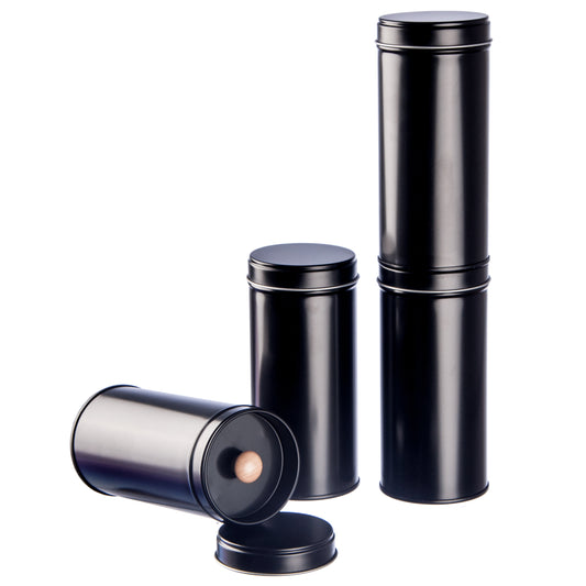 6 schwarze Teedosen mit Aromadeckel und 6 Etiketten, nebeneinander stehend.