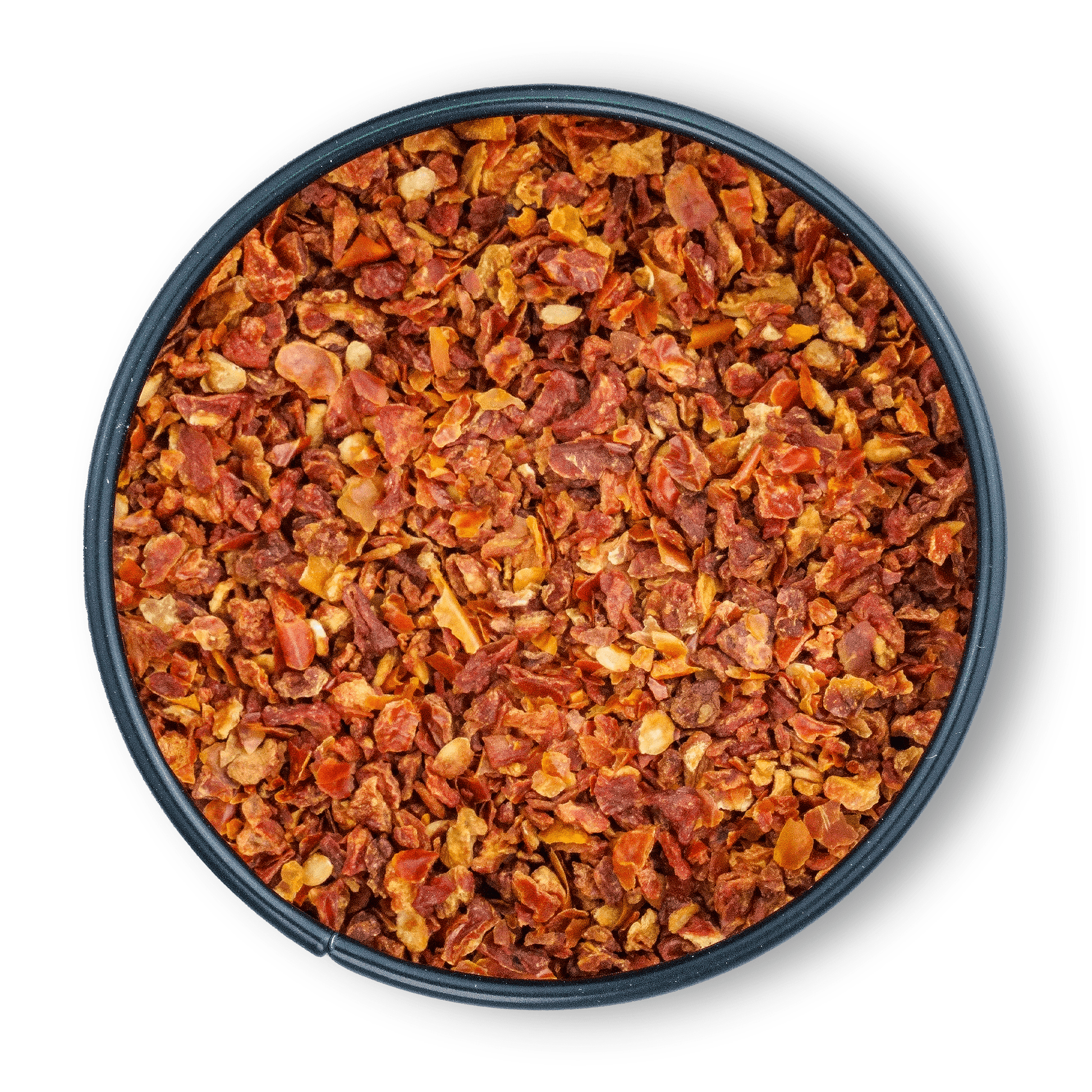 Schale mit groben Bio Tomatenflocken und Chili-Flocken auf weißem Hintergrund, Draufsicht.