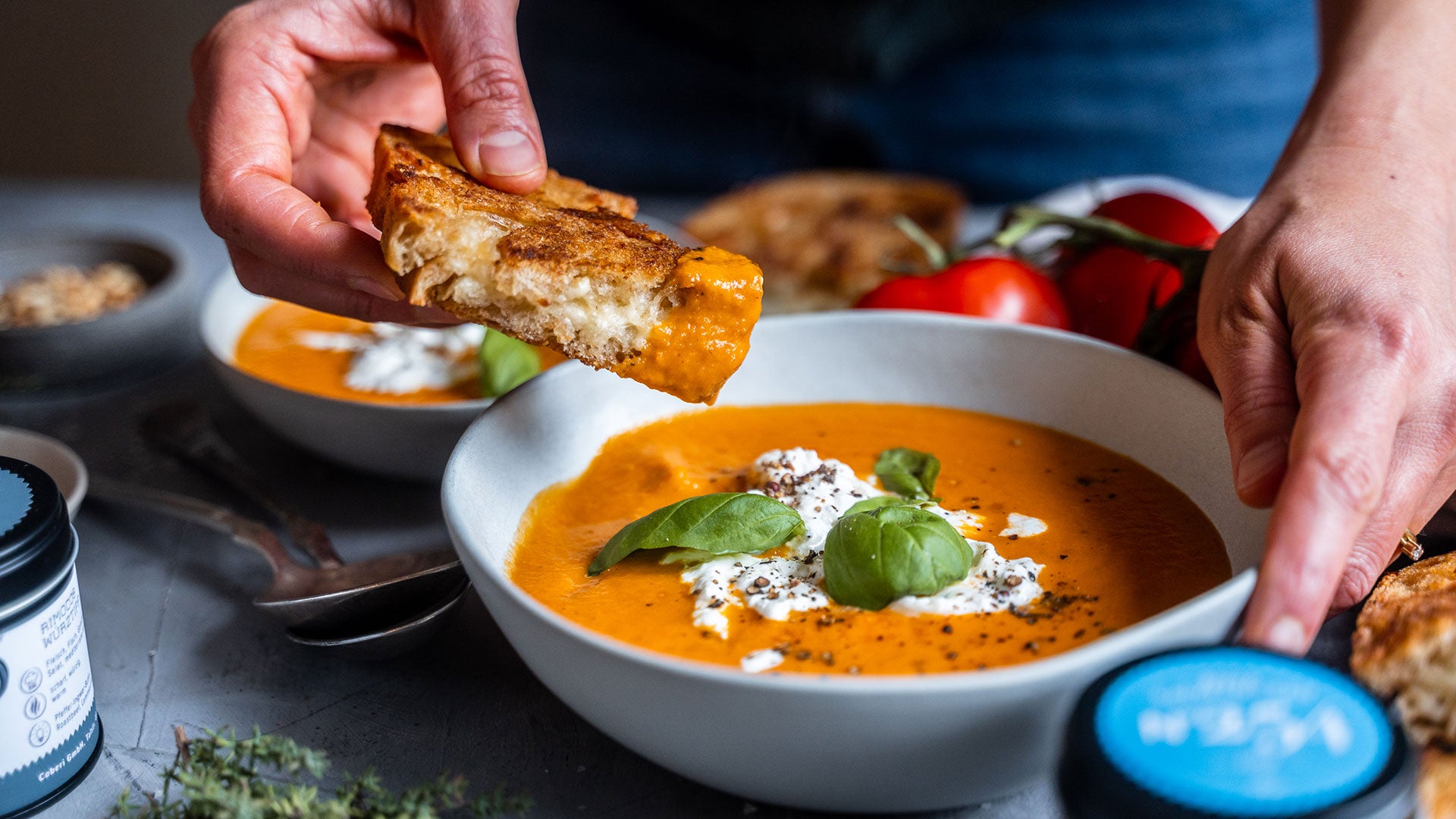Gegrilltes Käsebrot wird in cremiger Tomatensuppe mit frischen Basilikumblättern getaucht.